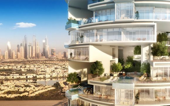 Immeuble résidentiel luxueux de plusieurs étages avec balcons en verre et plantes vertes luxuriantes, surplombant un horizon de gratte-ciel modernes dans la ville ensoleillée de Five JVC.