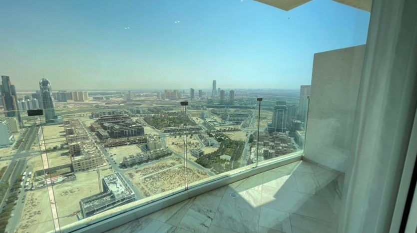 Vue depuis un immeuble de grande hauteur de Five JVC présentant un paysage urbain tentaculaire en contrebas, visible à travers de grandes fenêtres d'angle dans une pièce au sol en marbre.