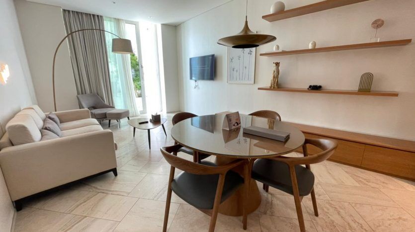Salon moderne avec une table à manger ronde en bois, cinq chaises et un lampadaire arqué. Comprend un canapé blanc, des étagères minimalistes et du parquet clair.