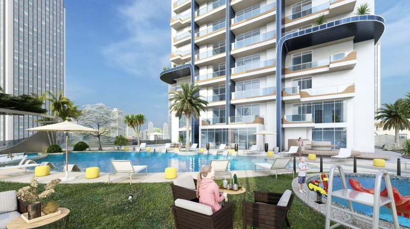 Piscine extérieure luxueuse d'un immeuble résidentiel de grande hauteur à Samana Waves Dubai avec chaises longues, parasols et verdure luxuriante, créant une oasis urbaine relaxante.