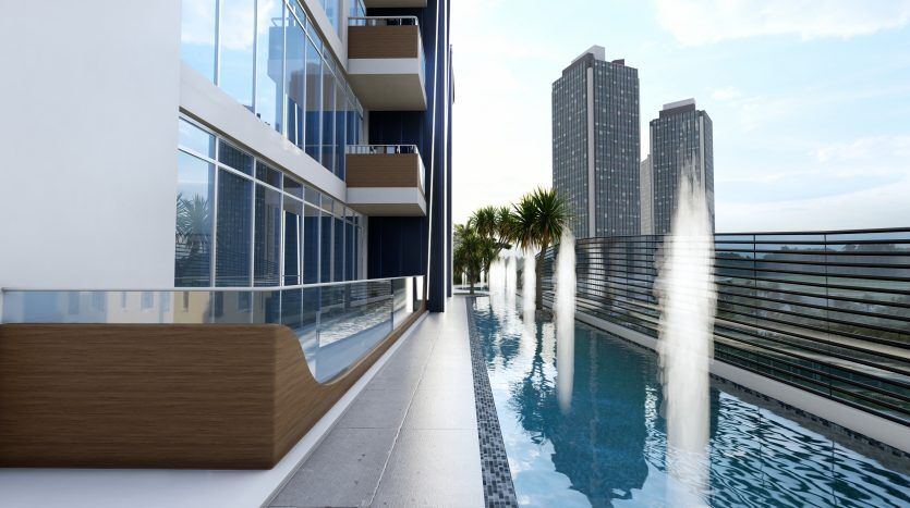 Balcon d'appartement moderne avec une piscine étroite à Samana Waves, surplombant les grands immeubles de la ville de Dubaï sous un ciel bleu clair.