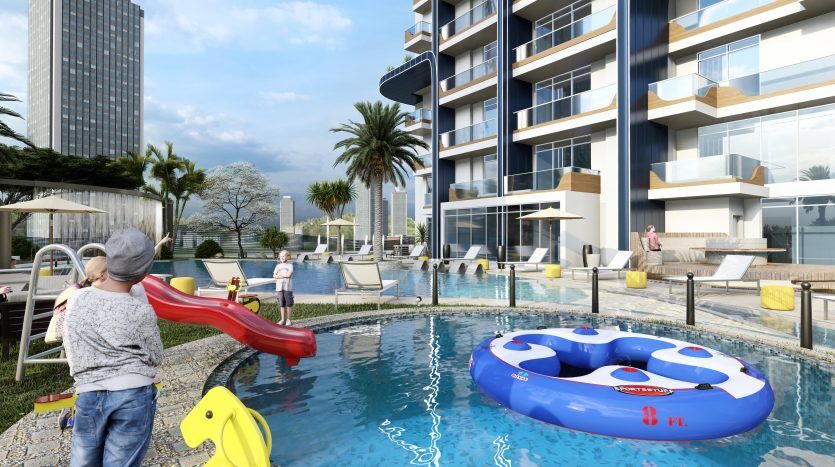 Une scène de piscine extérieure animée dans le luxueux complexe Samana Waves Dubai avec des enfants qui jouent, une architecture moderne, une verdure luxuriante et un fond pittoresque avec des gratte-ciel.