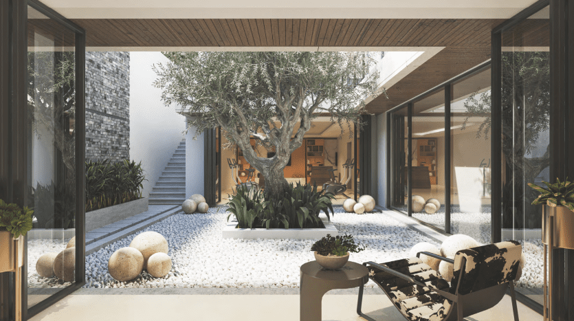 Cour moderne avec un grand olivier entouré de pierres blanches, flanqué de murs de verre et un plafond en bois, doté d'un mobilier minimaliste et de pierres sphériques décoratives. Idéal pour investissement Dubaï.