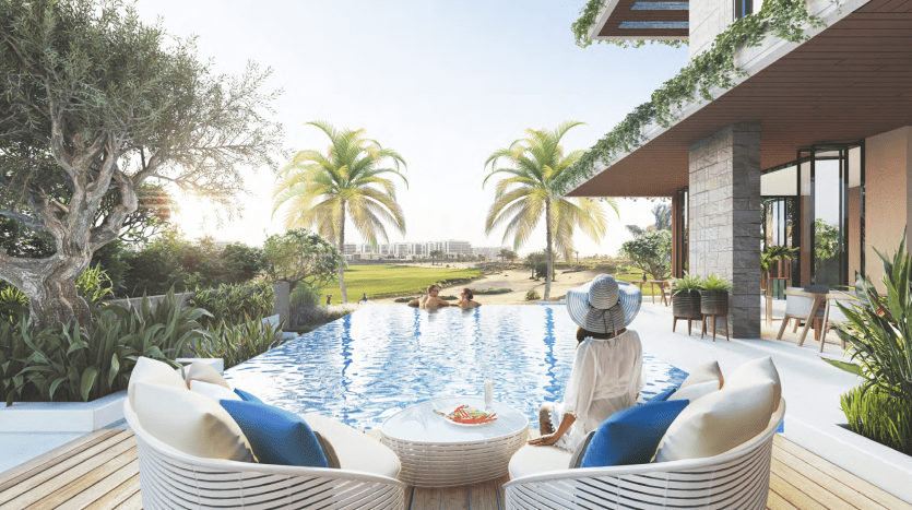 Une femme portant un chapeau de soleil profite d'une vue sereine au bord de la piscine dans une luxueuse villa de Dubaï, avec des palmiers et l'océan au loin.