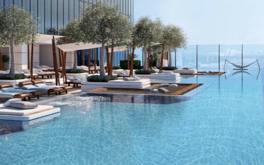 Ein luxuriöser Infinity-Pool auf dem Dach mit hellblauem Wasser, umgeben von Bäumen, Liegestühlen und Hütten, mit Panoramablick auf den Ozean von einem prestigeträchtigen Standort in Dubai Immobilien.
