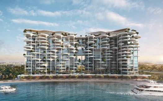 Ein modernes und luxuriöses Apartmentgebäude am Meer in Dubai mit mehreren Balkonen, weitläufigen Glasfassaden und mit grünen Dächern gekrönt. In der Nähe liegen mehrere Jachten in einem hellblauen Gewässer vor Anker.