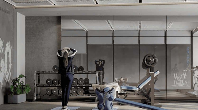 Trois personnes s'étirant et faisant de l'exercice dans une salle de sport moderne dotée de grandes fenêtres, de tapis d'exercice et de divers équipements de gymnastique dans une villa exclusive à Dubaï.