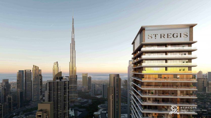 Aerial view of an urban landscape at dusk, with the St. Regis Hotel in the foreground and the imposing Burj Khalifa in the background, under a clear sky with prominent Dubai apartment buildings