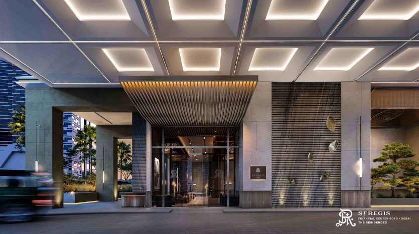 Exterior view of the St. Regis Hotel entrance at dusk, featuring modern architecture with lighted ceilings, elegant wood paneling and glass doors, on a Dubai street scene.