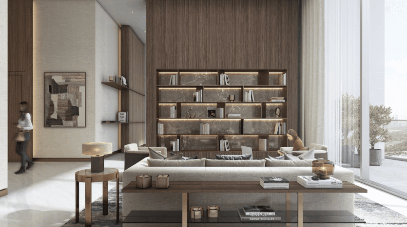 A spacious living room in a villa in Dubai with large windows, modern furniture and a wooden shelf filled with books and decorations. Two people are relaxing in the room, one reading by the window and