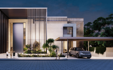 Maison moderne de deux étages à l'architecture minimaliste, présentant des lignes épurées et un mélange de lattes de bois et de façades en pierre lisse. On voit une famille se diriger vers l'entrée tandis qu'une voiture est garée sous un parking adjacent.
