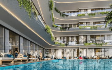 Cour d'hôtel moderne avec une grande piscine, des balcons à plusieurs étages ornés de plantes et des clients se relaxant sur des chaises longues au bord de la piscine. Des jouets flottants se trouvent dans la piscine, notamment un ballon de plage gonflable. Un éclairage chaleureux met en valeur le design contemporain.