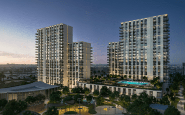Une vue nocturne du complexe d'appartements Hillsedge révèle deux hauts bâtiments ornés de nombreux balcons. Ils entourent une cour centrale présentant une piscine éclairée et des jardins bien entretenus, tandis que le ciel passe élégamment du crépuscule à l'obscurité.