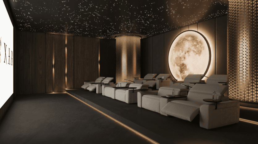 A luxurious home cinema with plush recliners, starry lights on the dark ceiling, a large illuminated moon mural and decorative lattice columns. A large screen is visible on the left.