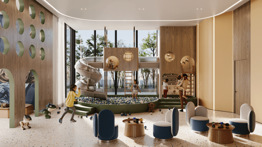 Modern indoor playroom with climbing structures, large spiral slide, ball pool and children's games. Large windows let in natural light; round tables and soft armchairs are arranged in the foreground. Trees can be seen outside.