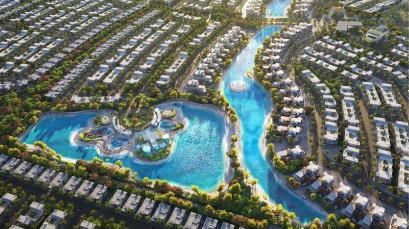 Vue aérienne de Damac Islands 2, une grande communauté résidentielle comprenant des canaux sinueux d'eau bleue, un lagon central avec une île, et des rangées de maisons modernes entourées de verdure.