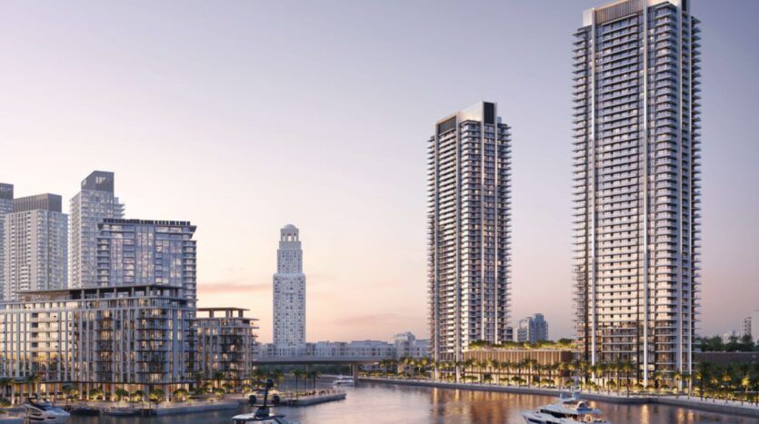 Des tours modernes et des appartements en bord de mer entourent le port de plaisance de Creek Bay, avec des yachts, des palmiers et une voie d'eau calme, sous un ciel doux en début de soirée.