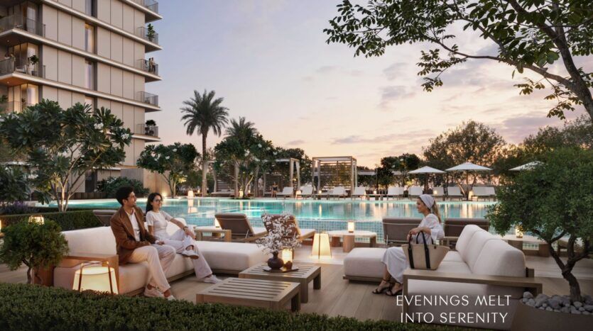 Un luxueux salon au bord de la piscine au coucher du soleil, avec des personnes se relaxant sur des canapés modernes en plein air, entourées d'arbres et de verdure à Creek Bay. Des bâtiments élégants se trouvent à l'arrière-plan. Le texte indique : "EVENINGS MELT INTO SERENITY.