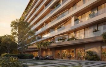 Lunaya Terraces est un immeuble d'appartements moderne de plusieurs étages, doté de grands balcons, d'espaces verts abondants et de baies vitrées. Deux voitures de luxe sont garées devant, tandis que des coins salon en plein air et un aménagement paysager luxuriant entourent le site.