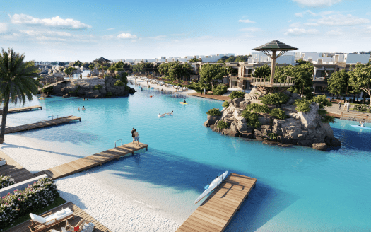 Un complexe luxueux à Damas Hills 3 doté d'un grand lagon bleu artificiel avec des plages de sable fin, des palmiers, des falaises et plusieurs piscines, où les gens pratiquent diverses activités nautiques sous un ciel dégagé.