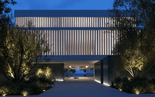 Bâtiment moderne de Dubaï éclairé au crépuscule avec un design symétrique comportant une passerelle centrale menant sous une grande structure surélevée flanquée de rangées d'arbres.
