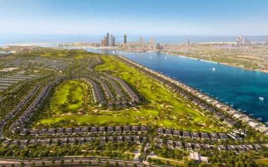 Vue aérienne d'une grande ville au bord de l'eau, avec Hudayriyat Golf Estates, des parcs verdoyants, des zones résidentielles et des gratte-ciel au loin, bordée par une baie et la mer, sous un ciel bleu clair.