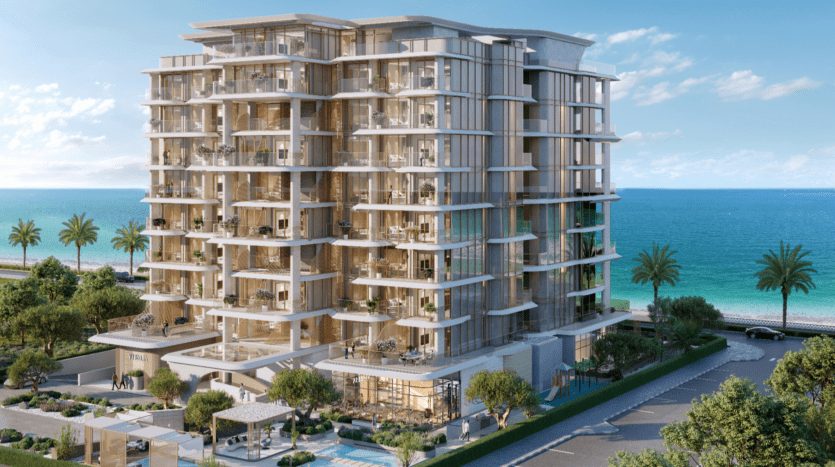 Un immeuble moderne de plusieurs étages avec balcons surplombant l'océan, rappelant les structures luxueuses de Vitalia Palm Jumeirah. Des palmiers bordent la rue et le ciel est dégagé avec quelques nuages. Le cadre est serein, avec une végétation luxuriante enveloppant la structure.