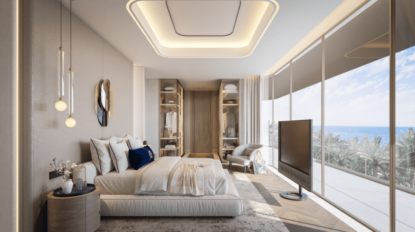 La chambre Vitalia moderne avec ses baies vitrées offre une vue imprenable sur l'océan à Palm Jumeirah. Elle dispose d'un grand lit, d'une télévision murale, d'un éclairage contemporain et d'une décoration élégante dans des tons neutres. Un dressing est visible sur le côté gauche.