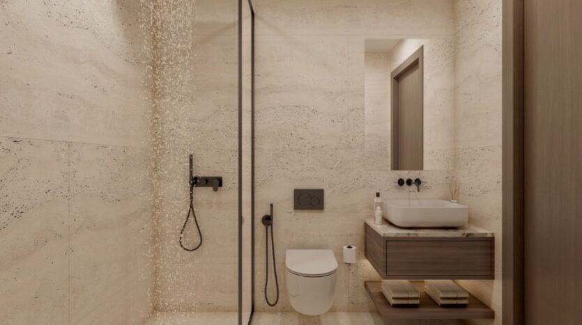 Salle de bains moderne aux murs en pierre beige, dotée d'une douche à l'italienne avec pomme de douche à effet pluie, de toilettes suspendues, d'un meuble-lavabo suspendu avec vasque posée et d'étagères ouvertes — le tout conçu avec raffinement dans le style « Beverly Crown » de HMB.
