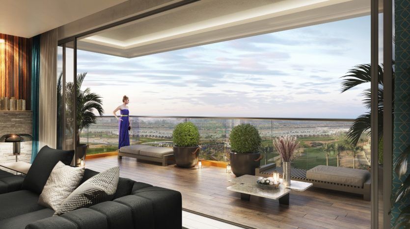 Une femme vêtue d’une robe bleue se tient près de grandes fenêtres dans un salon élégant, regardant un paysage verdoyant et luxuriant sous un ciel couchant. La pièce présente un mobilier moderne et des plantes d'intérieur représentant le