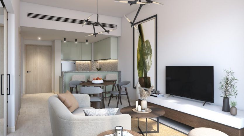 Salon moderne dans une villa de Dubaï avec coin repas ; comprend un canapé beige, une table basse circulaire, une télévision murale et une table à manger pour quatre personnes, avec une cuisine élégante en arrière-plan.