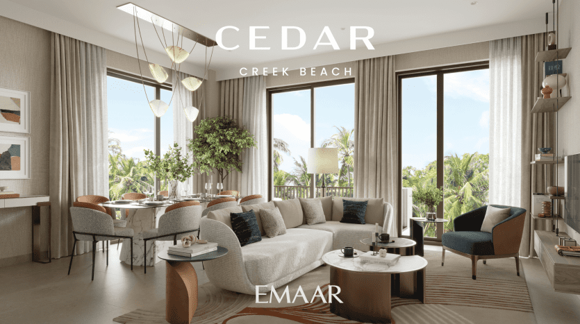 Un salon luxueux en bord de mer dans un appartement de Dubaï avec de grandes fenêtres offrant une vue sur les palmiers, décoré dans des tons neutres, avec des sièges moelleux, des accents en bois et une décoration élégante. La pièce porte la marque