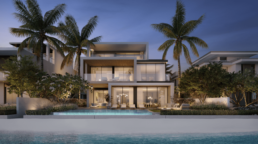 Modern, luxurious beachfront apartment in Dubai with light-filled interiors, large balconies and a pool surrounded by palm trees at dusk.