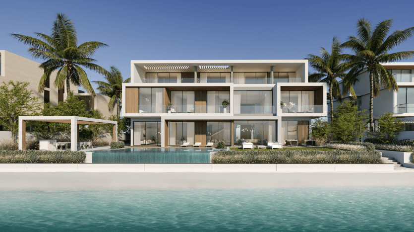 Modern beachfront villa in Dubai with large glass windows, several balconies and a swimming pool surrounded by palm trees under a clear blue sky.