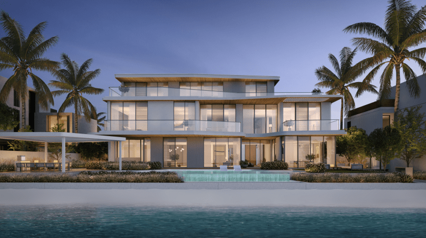 Modern, luxurious two-storey beachfront house in Dubai, lit at dusk, with large glass windows, several balconies, swimming pool and surrounded by palm trees.