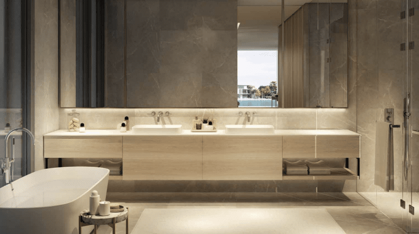 A luxurious bathroom in a Dubai apartment featuring a long wooden basin with two sinks, large mirrors, an island bathtub and a view of an outdoor balcony. The room is lit by soft light,