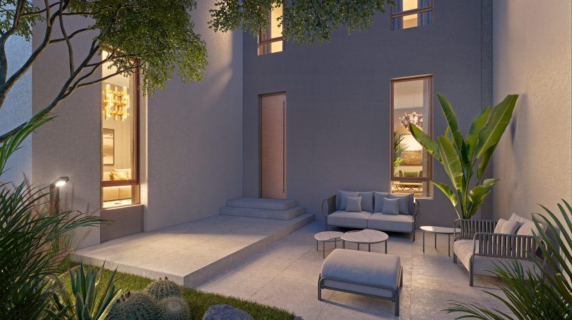 Patio extérieur confortable d'une maison moderne de Dubaï au crépuscule, doté d'un éclairage élégant, de sièges confortables, de plantes luxuriantes et d'une ambiance sereine.