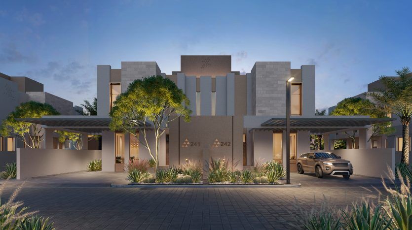 Immeuble résidentiel moderne à Dubaï au crépuscule avec une voiture garée sous l'auvent d'entrée, entouré de verdure paysagée et de palmiers.