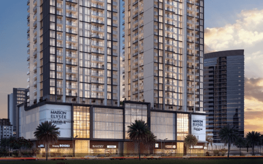 Un immeuble moderne de grande hauteur au crépuscule, avec des vitrines éclairées, dont la « Maison Elysée » et plusieurs boutiques au niveau de la rue, sur un ciel crépusculaire à Dubaï.