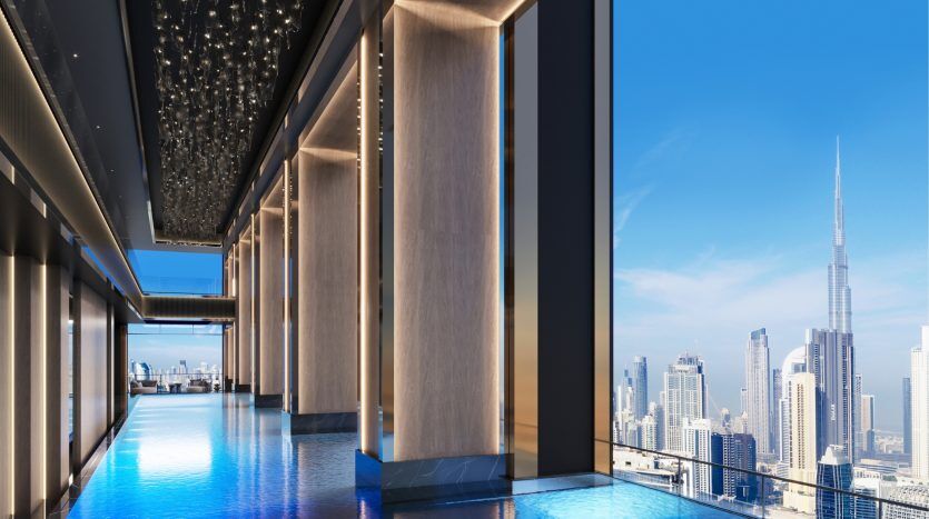 Interior view of a luxurious swimming pool in a high-rise apartment in Dubai overlooking the rooftops of a modern city with a clear blue sky.