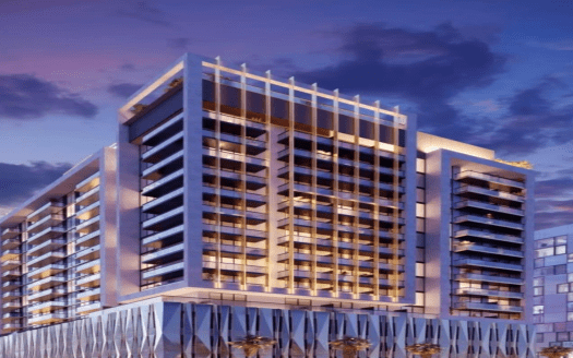 Un immeuble moderne de grande hauteur illuminé au crépuscule à Dubaï, doté de fenêtres en verre réfléchissantes et de poutres horizontales sur sa façade, sur un ciel vibrant avec des nuages.