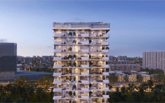 Un immeuble moderne de grande hauteur nommé « IMTIAZ » se dresse bien en évidence sur un paysage urbain crépusculaire. Le bâtiment comporte plusieurs étages avec de grands balcons en verre ornés de plantes. Les bâtiments de la ville environnante et la verdure sont visibles en arrière-plan.