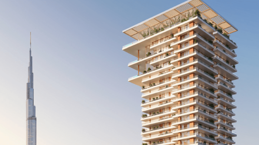 Immeuble moderne de grande hauteur doté de balcons décalés et d'un jardin sur le toit, les résidences Fairmont se dressent fièrement sur un ciel bleu clair. Le Burj Khalifa est visible au loin.