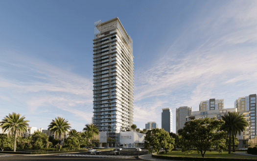 Le gratte-ciel moderne et de grande hauteur connu sous le nom de Skyhills 2 arbore une façade en verre saisissante, se dressant fièrement sur un ciel partiellement nuageux. Entouré de palmiers et d'une végétation luxuriante, il domine des bâtiments plus petits tandis que quelques voitures passent sur la route en face.