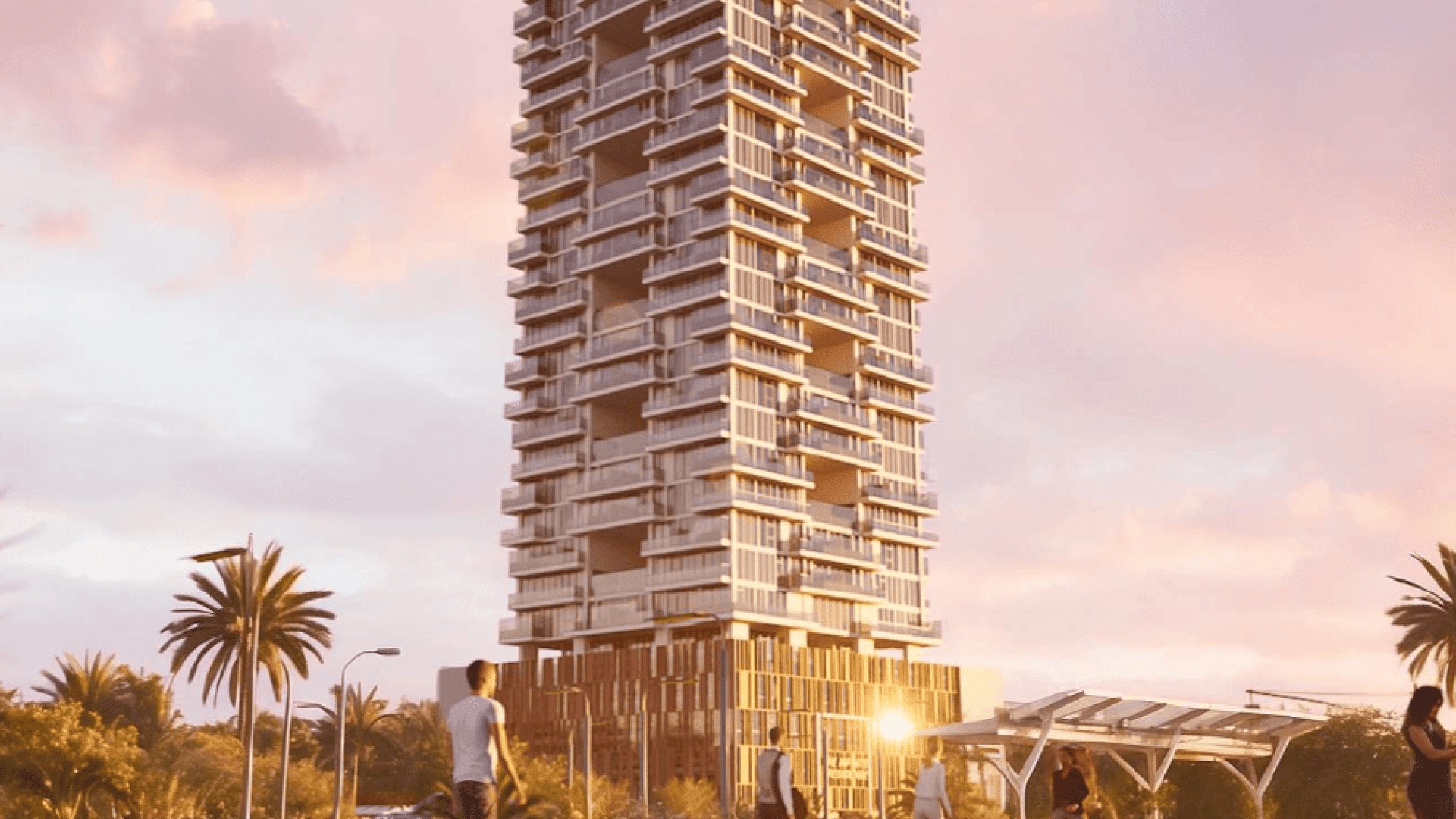 Un gratte-ciel moderne de grande hauteur, au design unique et étagé, se dresse sur un ciel rose et orange au coucher du soleil. Des palmiers et quelques personnes sont visibles au premier plan, ce qui confère une atmosphère animée à la scène.