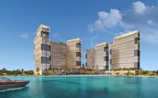 Une vue imprenable sur le front de mer de Damac Maritime City met en valeur trois gratte-ciel modernes aux lignes verticales distinctes et aux toits végétalisés. Au premier plan, un bateau à moteur glisse sur l'eau turquoise, tandis que le ciel clair n'est parsemé que de quelques nuages.