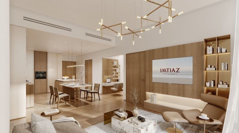 Un salon et une salle à manger modernes et ouverts au Wynwood Horizon de Imtiaz, avec des sols en bois, des meubles neutres, des lustres dorés, une télévision murale affichant "IMTIAZ" et une décoration minimaliste élégante.