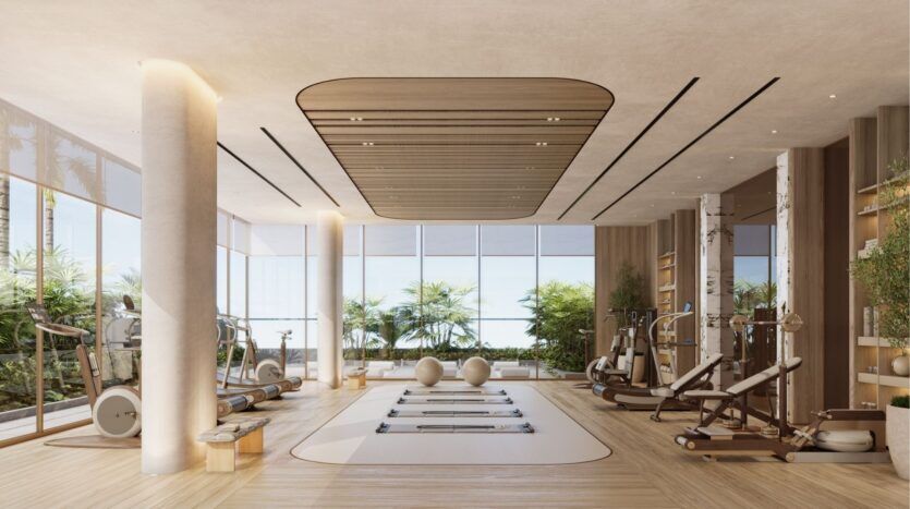 Cette salle de sport moderne située à Wynwood Horizon de Imtiaz est dotée de grandes fenêtres, de planchers en bois clair, de réformateurs de pilates, de ballons de gymnastique et de machines d'exercice. Lumineuse et minimaliste, elle offre des accents naturels avec une verdure luxuriante visible à l'extérieur.