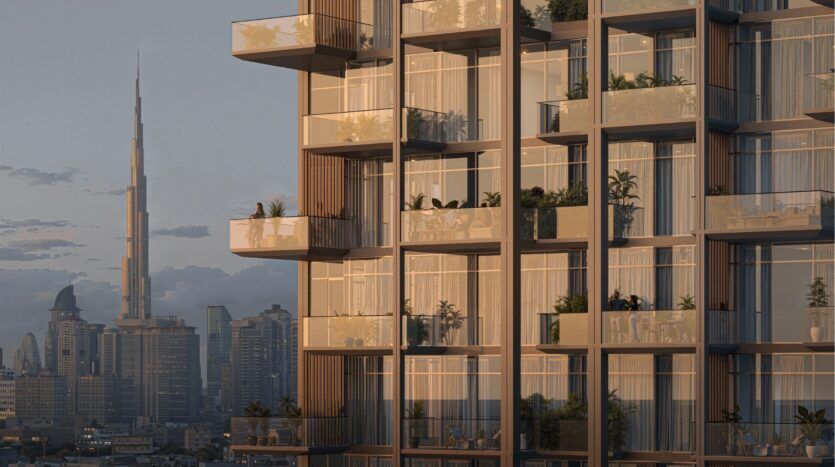Immeuble d'appartements moderne avec balcons en verre et plantes en pot au premier plan ; à l'arrière-plan, la ligne d'horizon de la ville avec le Burj Khalifa au coucher du soleil, capturant parfaitement l'allure vibrante de l'horizon de Wynwood de Imtiaz.