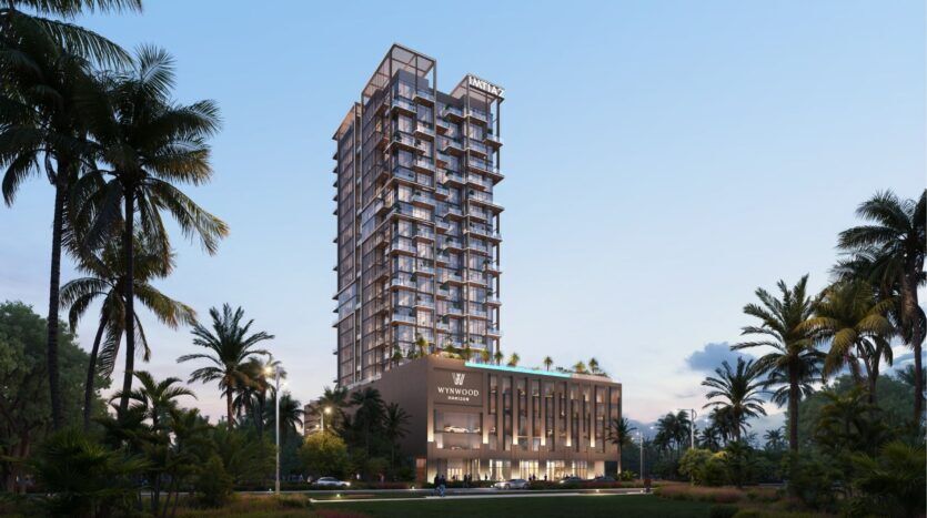 La tour moderne "Wynwood Horizon de Imtiaz", dotée de nombreux balcons, s'illumine au crépuscule au milieu des palmiers et de la verdure luxuriante, sous un ciel dégagé.